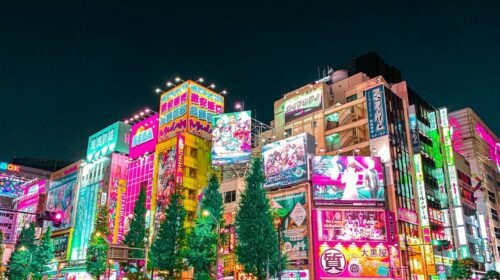 a group of people walking around a city at night