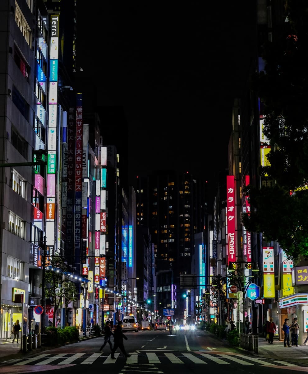 a couple of people crossing a street at night